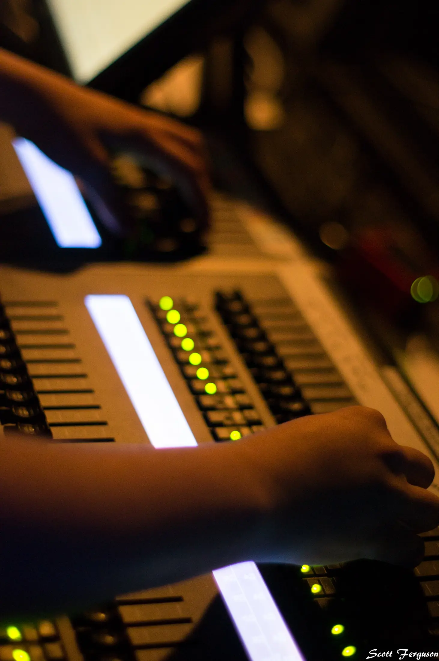 A crew member's hands on a lit console in the booth