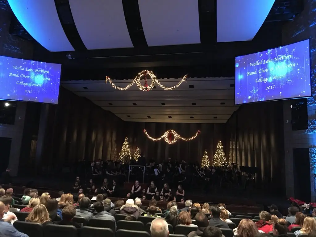 A holiday band and choir concert with projection screens on both sides of the stage