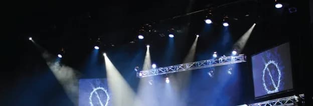 Beams of light cutting through haze over a stage with a lighting truss